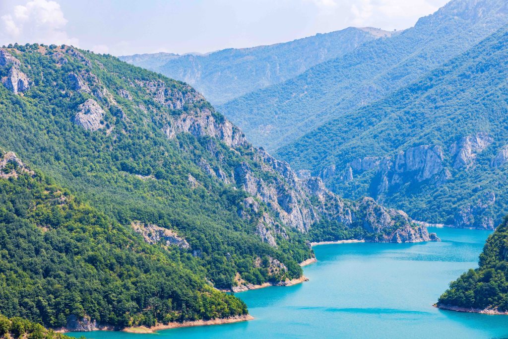 Aerial View Of Piva Lake Or Pivsko Jezero Between Hills Covered With Green Trees