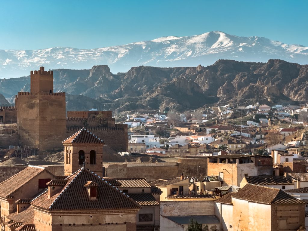 Scenic View Of Guadix, Spain With Castle, Cave Houses, And Mountains